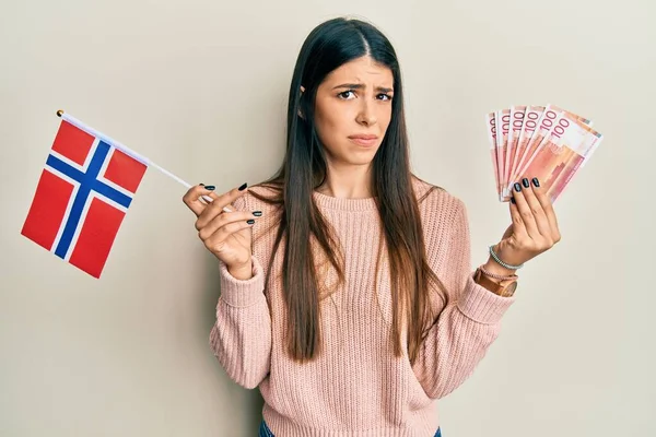 Mladá Hispánka Držící Norskou Vlajku Korunové Bankovky Bezradný Zmatený Výraz — Stock fotografie
