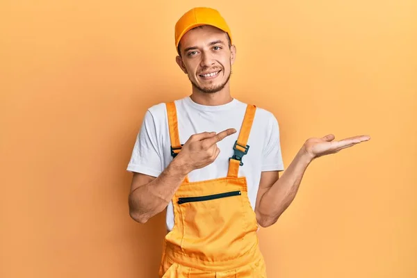 Hispanic Ung Man Bär Händig Uniform Förvånad Och Ler Mot — Stockfoto