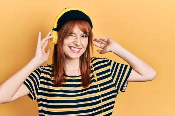 Pelirroja Mujer Joven Escuchando Música Usando Auriculares Guiñando Ojo Mirando —  Fotos de Stock