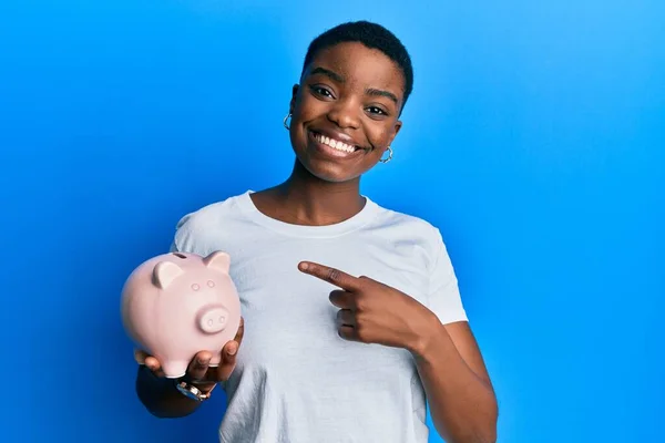 Mladý Africký Americký Žena Držení Prasátko Banka Úsměvem Šťastný Ukazující — Stock fotografie