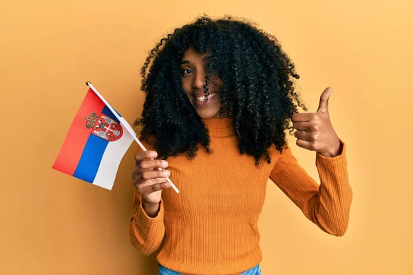 Afroamerykanka Afro Włosy Trzymając Flagę Serbii Uśmiechnięty Szczęśliwy Pozytywny Kciuk — Zdjęcie stockowe
