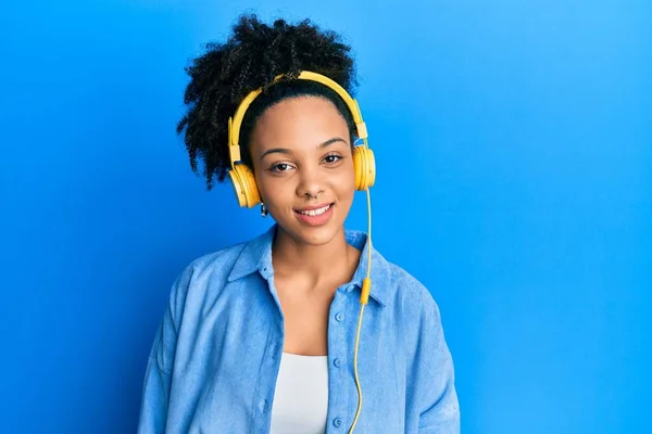 年轻的非洲裔美国女孩 一边用耳机听音乐 一边站在那里 面带微笑 脸上带着自信的笑容 露出了牙齿 — 图库照片