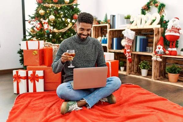 Młody Afroamerykanin Świętuje Boże Narodzenie Pijąc Szampana Korzystając Laptopa Domu — Zdjęcie stockowe