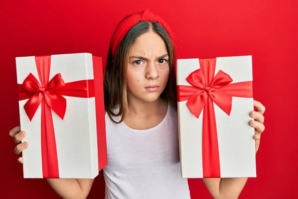 Beautiful Brunette Little Girl Holding Gifts Skeptic Nervous Frowning Upset — Stock Photo, Image