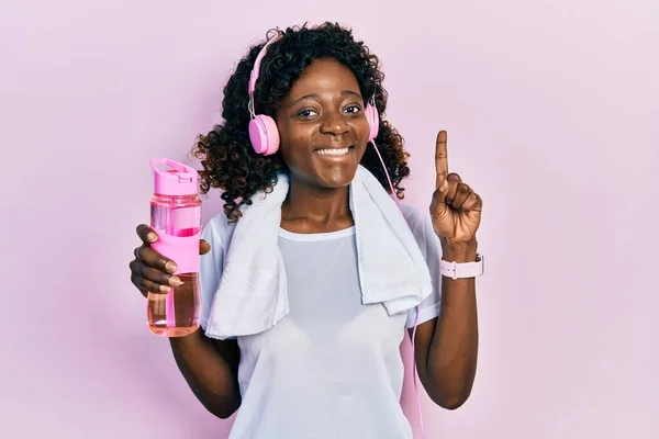 Молода Афроамериканська Жінка Спортивному Вбранні Тримає Пляшку Водою Допомогою Навушників — стокове фото
