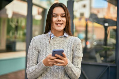 Parkta telefonla gülümseyen İspanyol turist kız.