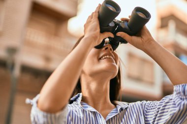 Şehirde dürbünle gülümseyen genç İspanyol kız..