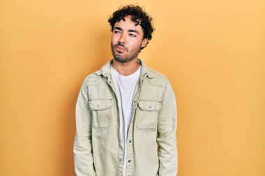 Gündelik kıyafetler giyen genç İspanyol adam gülümseyip yan tarafa bakıyor ve düşünüyor.. 