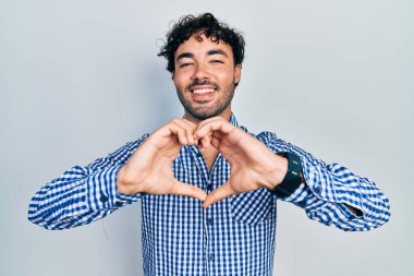 Gündelik kıyafetler giyen, aşık gülümseyen, elleriyle kalp sembolü yapan genç bir İspanyol. romantik kavram. 