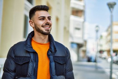 Yakışıklı, sakallı, neşeli ve kendine güvenen, kışlık palto giyen bir İspanyol.