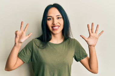 Gündelik tişört giyen genç İspanyol kız sekiz numarayı gösterip işaret ederken kendinden emin ve mutlu bir şekilde gülümsüyor.. 