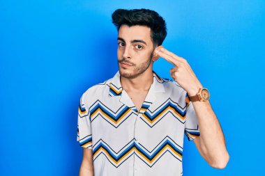 Gündelik giysiler giymiş genç İspanyol bir adam kendini vuruyor ve öldürüyor. Elini ve parmaklarını silah gibi kullanıyor. İntihar jesti.. 