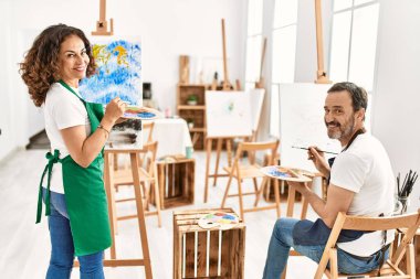 Resim stüdyosunda gülümseyen iki orta yaşlı öğrenci..