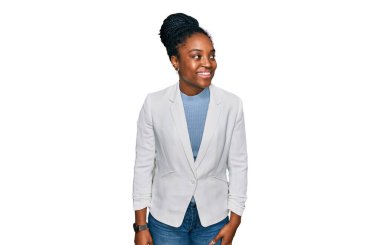 Genç Afro-Amerikan kadın iş kıyafetleri giyip yüzünde gülümseme, doğal bir ifade ile yan yana bakıyor. Kendinden emin gülen. 