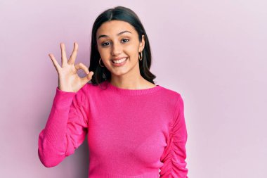 Gündelik kıyafetler giyen, gülümseyen genç İspanyol kadın el ve parmaklarıyla 