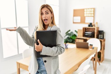 Ofisteki sarışın iş kadını avuç içlerini açıp fotokopi alanını gösteriyor. Reklam veriyor, gülümsüyor, mutlu bir şekilde gülümsüyor. 