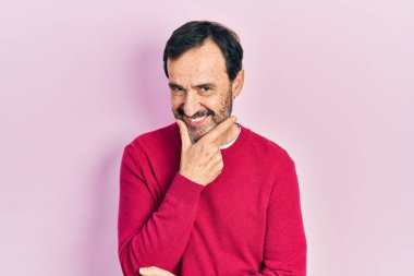 Orta yaşlı İspanyol bir adam gündelik kıyafetler giyiyor kameraya bakıyor kollarını kavuşturup gülümsüyor ve çenesini kaldırıyor. Olumlu düşünmek. 