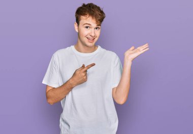 Beyaz gündelik tişört giyen genç beyaz bir adam kameraya hayret ediyor ve gülümsüyor.. 