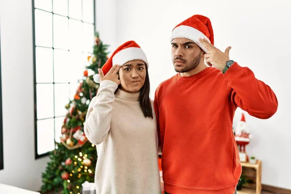 若いヒスパニック系のカップルがクリスマスツリーの撮影で立って銃のように頭に手と指を指して自分自身を殺す 自殺のジェスチャー — ストック写真