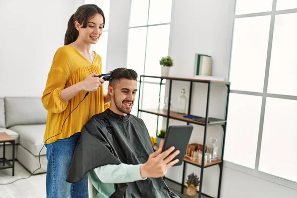 Jonge Latino Man Zoek Touchapd Scherm Terwijl Kapper Vrouw Knippen — Stockfoto