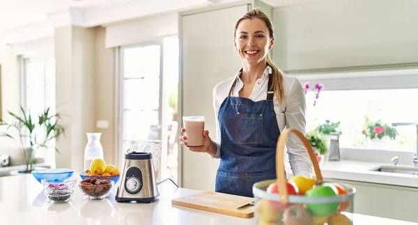 Güzel Sarışın Kadın Önlük Giyip Mutfakta Smoothie Içiyor Olumlu Mutlu — Stok fotoğraf