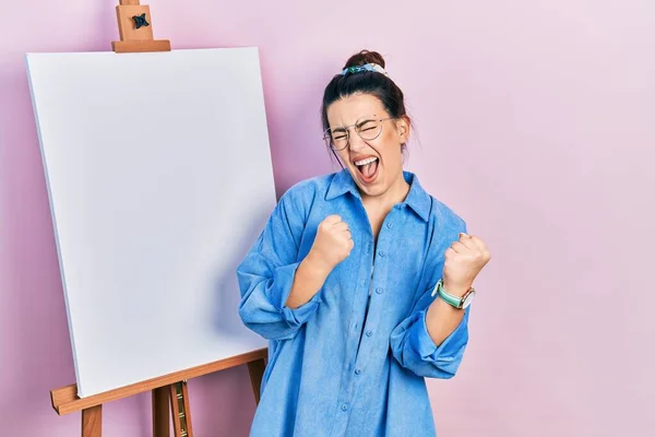 Young Hispanic Woman Standing Painter Easel Stand Celebrating Surprised Amazed — Stock Photo, Image