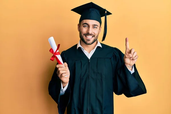 Joven Hispano Vestido Con Bata Graduación Sosteniendo Diploma Sonriendo Con — Foto de Stock