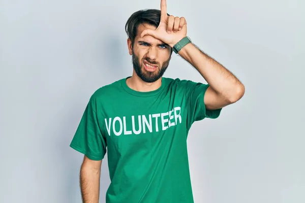 Jovem Hispânico Vestindo Camiseta Voluntária Zombando Pessoas Com Dedos Testa — Fotografia de Stock