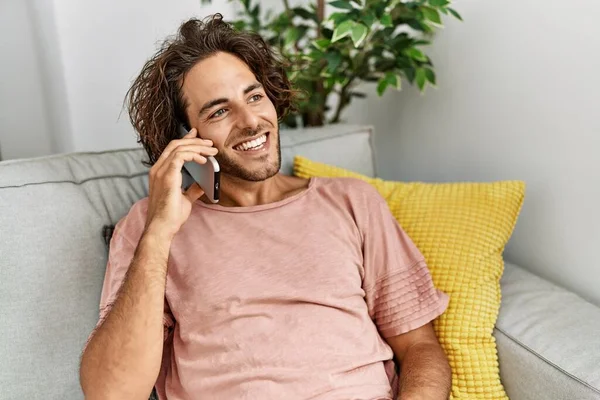 Joven Hombre Hispano Sonriendo Feliz Hablando Teléfono Inteligente Sentado Sofá —  Fotos de Stock