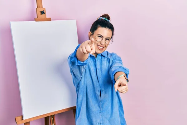 Young Hispanic Woman Standing Painter Easel Stand Pointing You Camera — ストック写真