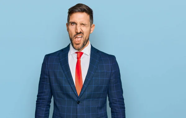 Handsome man with beard wearing business suit and tie winking looking at the camera with sexy expression, cheerful and happy face. — Stock Image Handsome Man Beard Wearing Business Suit Tie Winking Looking Camera Royalty Free Stock Photos
