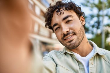 Yakışıklı, sakallı, güneşli bir günde mutlu bir şekilde gülümseyen ve selfie çeken bir İspanyol.
