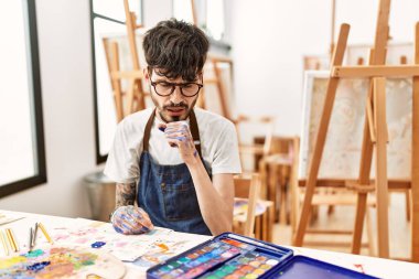 Sanat stüdyosunda sakallı İspanyol bir adam kendini kötü hissediyor ve soğuk algınlığı veya bronşitin belirtisi olarak öksürüyor. sağlık hizmeti kavramı. 