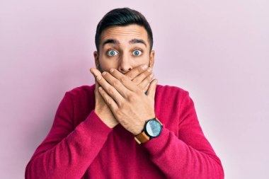 Gündelik kıyafetler giyen genç İspanyol adam yanlışlıkla elleri ile ağzını kapatırken şok oldu. gizli kavram. 