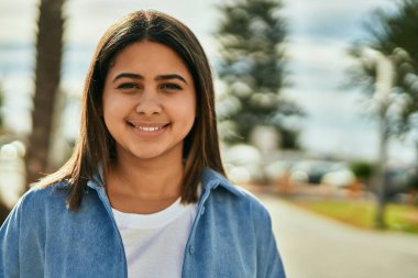 Genç Latin kız gülümseyerek şehirde mutlu mesut dikiliyor..