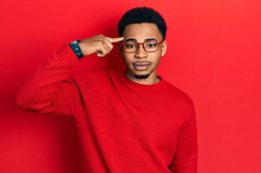 Genç Afro-Amerikalı bir adam kafasını parmağıyla göstererek yüzünde ciddi bir ifadeyle rahatladı. Basit ve doğal bir şekilde kameraya bakıyorsun.. 