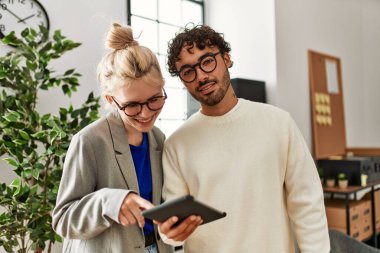 Ofiste dizüstü bilgisayarla çalışırken gülümseyen iki iş adamı.