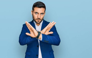 İş ceketi giyen genç İspanyol adam reddediliyor. Kollarını kavuşturup olumsuz işaret veriyor, kızgın surat yapıyor. 