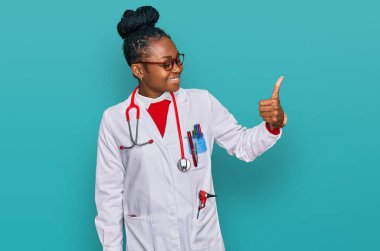 Genç Afro-Amerikan kadın doktor üniforması ve steteskop giyiyor. Gururlu görünüyor, gülümsüyor. 