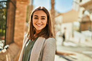 Genç İspanyol kız gülümseyerek şehirde mutlu mesut dikiliyor..