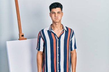 Genç İspanyol bir adam boş tuvalin yanında durmuş komik suratıyla yanaklarını şişiriyor. Havayla şişmiş ağız, çılgın bir ifade.. 