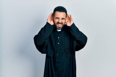 Sakallı, Katolik rahip cübbesi giyen yakışıklı İspanyol bir adam iki elini de kulak hareketi yaparken duymaya çalışıyor, dedikoduya meraklı. İşitme sorunu, sağır 