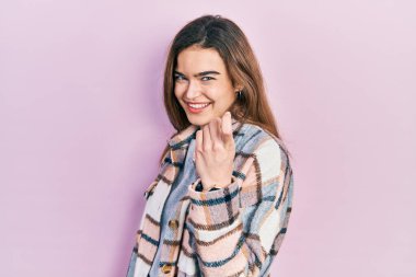 Kafkasyalı genç bir kız, günlük kıyafetler giymiş, el kol hareketi yaparak, mutlu bir şekilde karşılamaya ve gülümsemeye davet ediyor. 