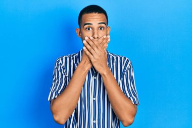 Gündelik giysiler giyen genç Afro-Amerikan bir adam yanlışlıkla elleri ile ağzını kapatırken şok oldu. gizli kavram. 