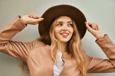 Genç sarışın kız gülümsüyor, mutlu bir şekilde şehirde duruyor..