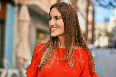 Genç İspanyol kadın gülümseyerek şehirde mutlu mesut dikiliyor..