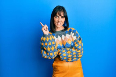 Genç İspanyol kadın, sıradan bir kazak giyiyor. Yüzünde kocaman bir gülümseme var. Elleri ve parmakları kameraya bakıyor.. 