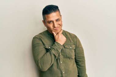 Gündelik kıyafetler giyen genç Latin bir adam bir soru hakkında endişeli ve gergin bir şekilde düşünüyor. 