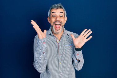 Gri saçlı, iş gömleği giyen yakışıklı, çılgın kutlama yapan, kolları havada ve gözleri açık heyecanlı bir şekilde başarıyı yakalayan orta yaşlı bir adam. Kazanan konsept 