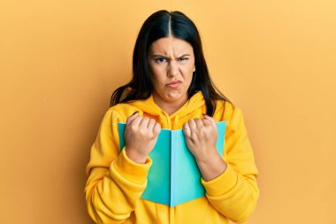 Güzel esmer kadın kitabı kuşkucu ve gergin tutuyor, sorun yüzünden surat asıyor. negatif kişi. 